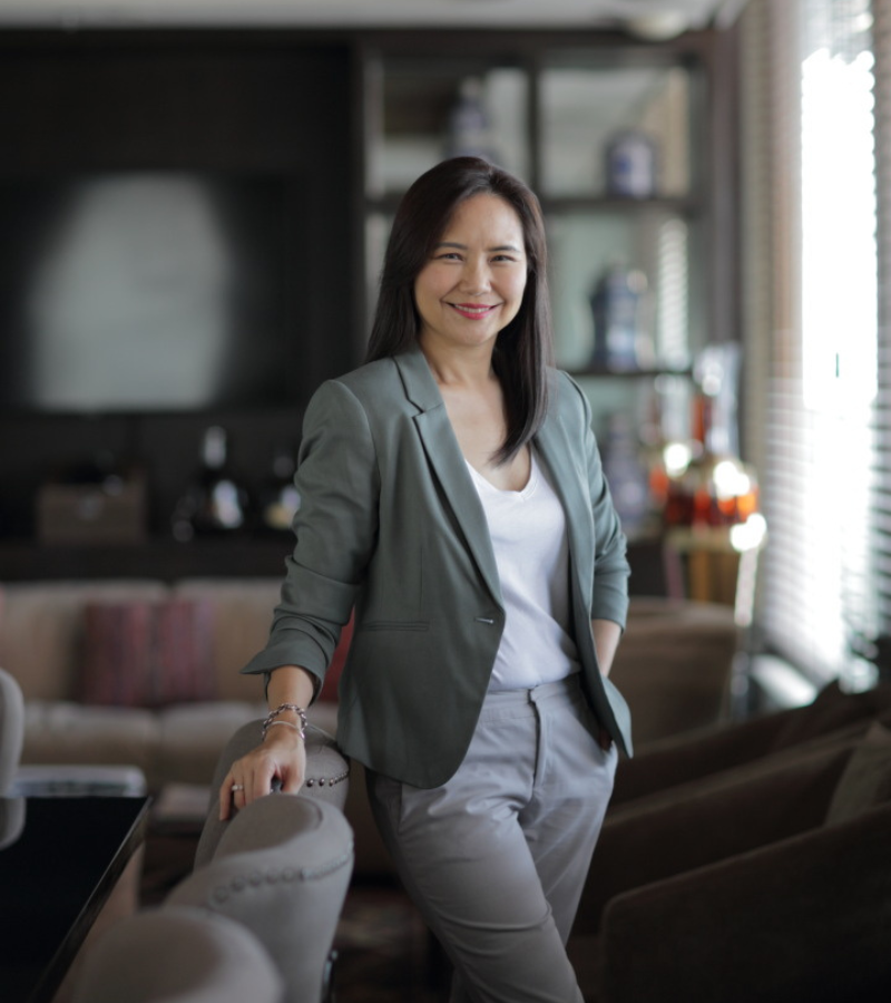 woman standing leaning on a chair with grey blazers on