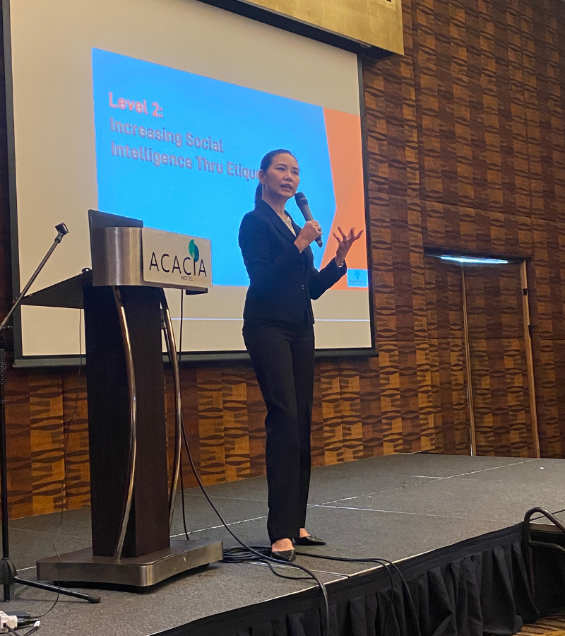 woman standing on stage explaning her slide