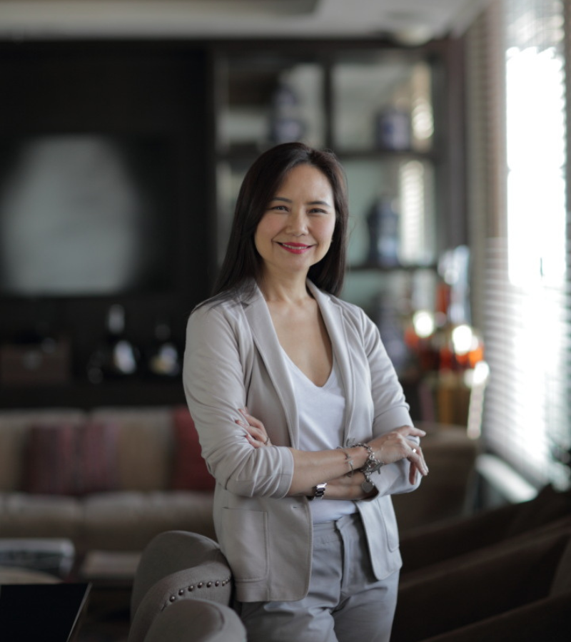 a woman with white blazer with cross arm posing leaning to a chair