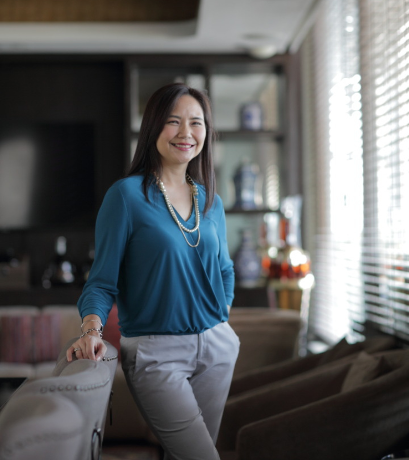 woman with a blue blazer standing leaning toward a chair